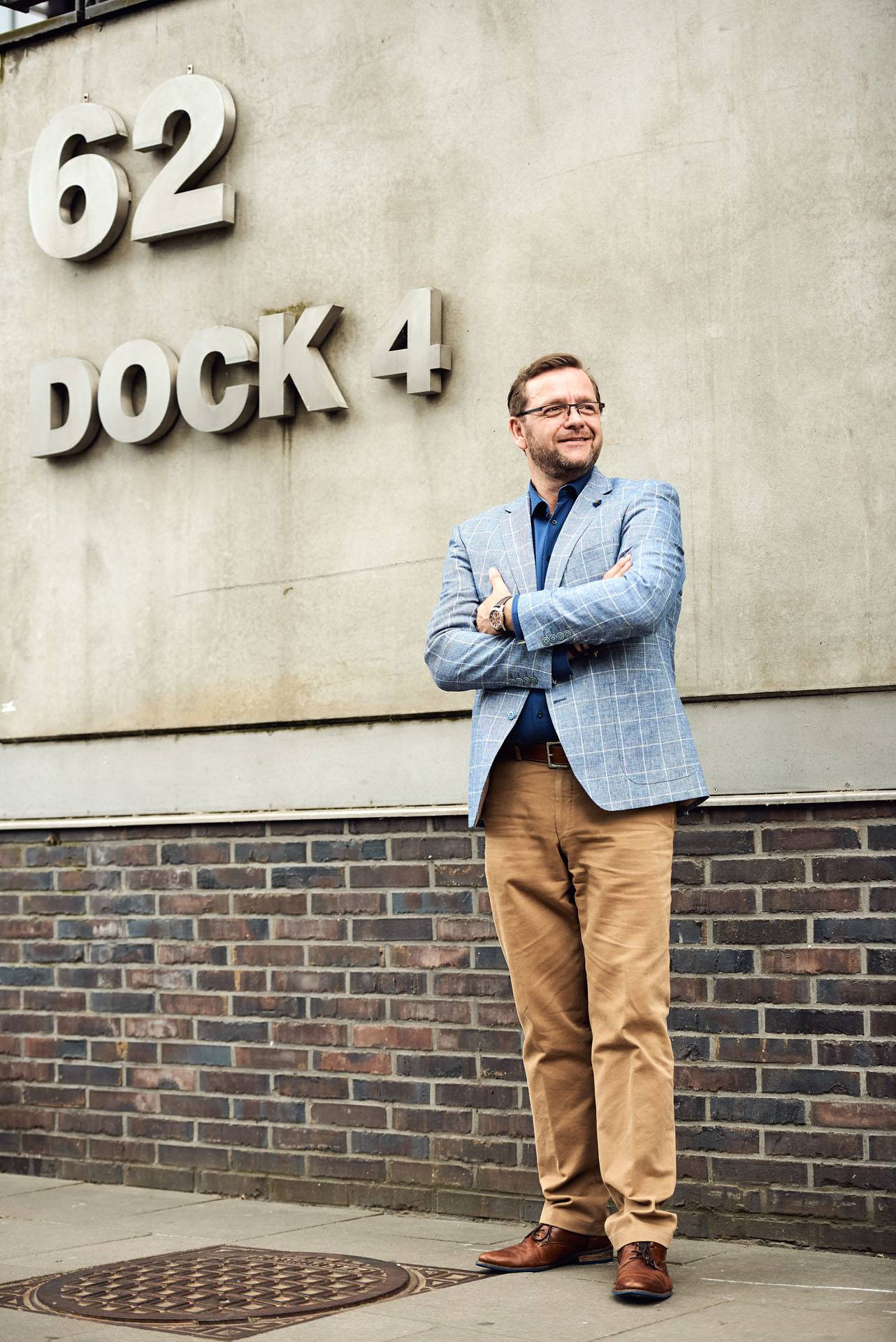 Hypnose-Therapeut im Anzug steht Portrait vor großen Buchstaben im Dock 4 im Hambuger Hafen